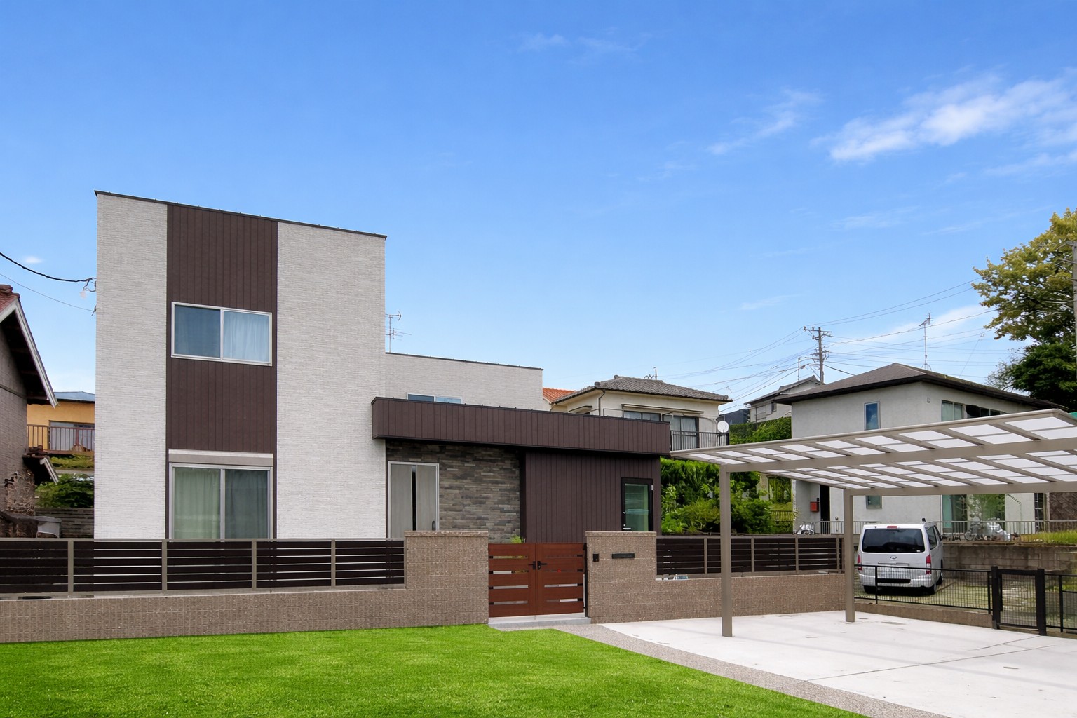 白と木目調の外壁が特徴の現代的な二階建て住宅の外観。